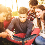 a group of people sitting on the grass looking at a book